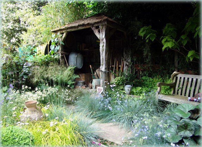 Простая деревянная скамейка, горшки, орудия труда - все это находится в саду среди простых цветов и трав